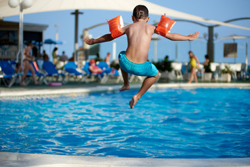 Caucasian boy having fun jumping into the pool.