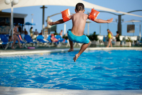 Caucasian boy having fun jumping into the pool.