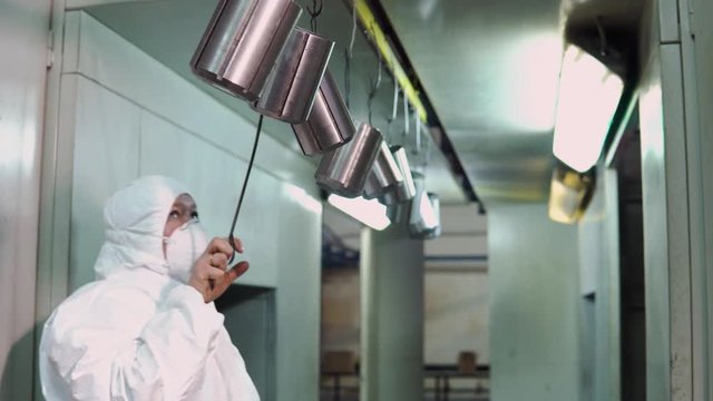 a man in a protective suit brings metal products to the painting shop
