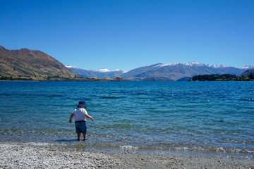 Fototapeta na wymiar A child explores the beautiful water of Lake Wanaka New Zealand.