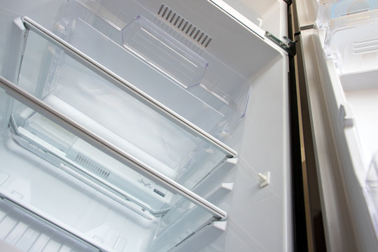 Open new fridge. Empty refrigerator with open door, view from below.