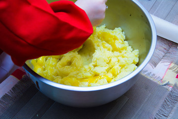 stirring dough in an iron bowl with a spoon