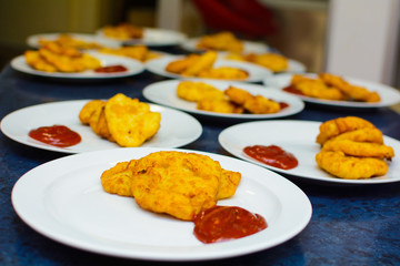 many servings of potato pancakes with ketchup on plates