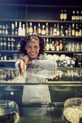 Young African entrepreneur shaking hands from behind her cafe co