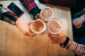 Cheers. Close-up top view of friends holding mugs with beer