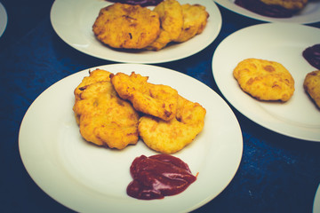 many servings of potato pancakes with ketchup on plates