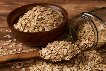 Oatmeal or oat flakes on old wooden table background, close-up. Healthy vegetarian diet food and agriculture concept