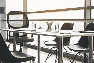 Table and chairs during business meeting. Different devices and stationery items are on surface