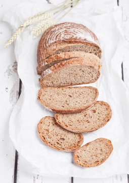 Freshly baked bread loaf with pieces on wood board