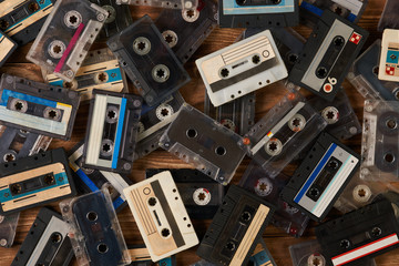 Large collection of retro cassette tape on old wooden table background, close-up