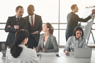 Young man and woman with concentrated expressions having brainstorm in boardroom