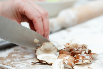 Woman cooking, slicing mushrooms on cutting board