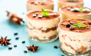 luxurious dessert Tiramisu in a glass on a blue background decorated with mint