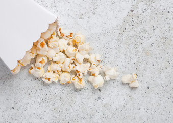 Paper container with fresh salted popcorn on stone
