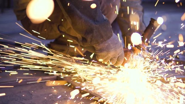 Close-up of worker cutting metal with grinder. Sparks while grinding iron
