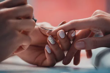 Foto op Aluminium Close-up van vrouwelijke handen die nagels lakken terwijl ze op tafel liggen © Yakobchuk Olena