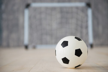 Fototapeta na wymiar A soccer ball in a small gate on a gray background. Mini football.