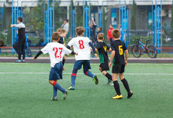 young boys play football, show dribbling, make passes to win on the summer spring  field