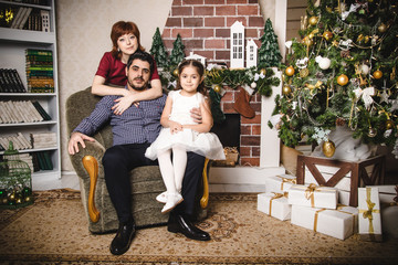 Obraz premium Family with Russian mom, Turkish dad and their daughter are in a room decorated for Christmas and new year