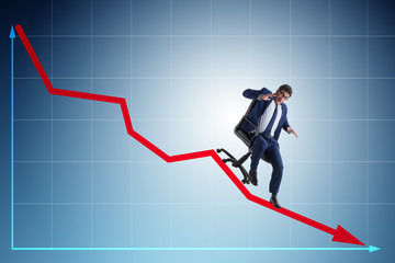 Businessman sliding down on chair in economic crisis concept