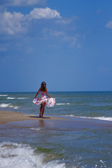 Fototapeta premium Fashion photo of happy beautiful young brunette girl at sea against water and blue sky. (travel, happiness, summer rest, freedom concept).