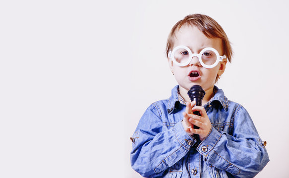 The famous actress. Humorous photocute child girl singing with a microphone (Happy childhood, teaching singing, music, child development concept)