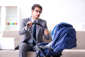 Businessman looking after newborn baby at home and teleworking