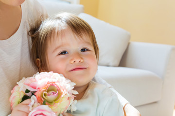 Happy toddler boy with his mother holding flowers