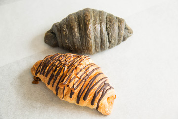 A chocolate croissant on white paper background