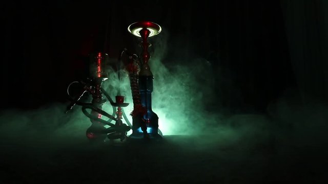 Hookah hot coals on shisha bowl making clouds of steam at Arabian interior. Oriental ornament on the carpet. Stylish oriental shisha in dark with backlight. For Shisha advertisement. Slider shot
