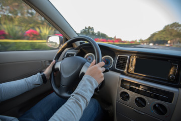 driver hands on wheel driving car on city street