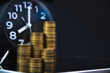 Coins stacks and alarm clock with tablet computer and financial graph, business planning vision and finance analysis concept