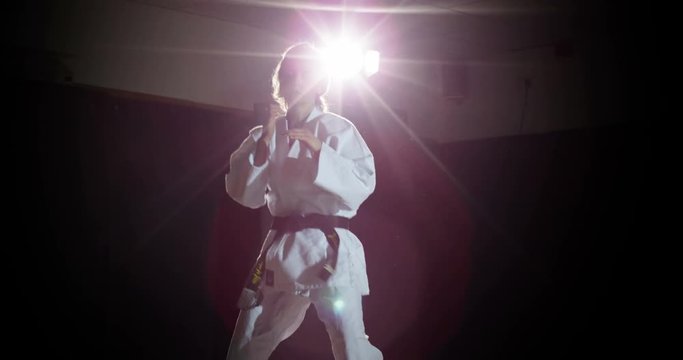A female martial arts instructor shadow practicing in slow motion.