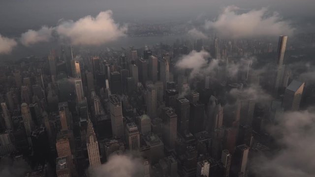 New York City aerial view of Midtown Manhattan at sunrise, featuring famous landmarks under low level clouds.