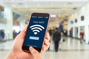 Free wi-fi concept.Hands holding mobile phone on blurred business man walking