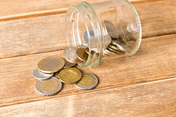 Various coins are scattered on a wooden table. The concept of poverty
