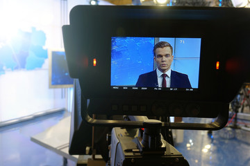 The news presenter reads the text on the teleprompter.Camera in the office. TV studio.