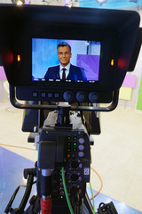 The news presenter reads the text on the teleprompter.Camera in the office. TV studio.
