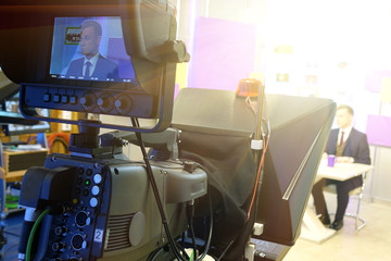 The news presenter reads the text on the teleprompter.Camera in the office. TV studio.
