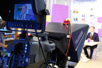 The news presenter reads the text on the teleprompter.Camera in the office. TV studio.
