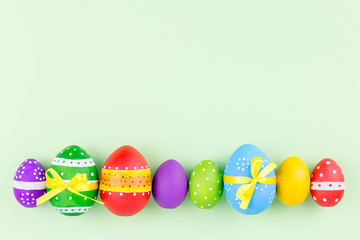 Colorful easter eggs on pastel green background flat lay. Copy space