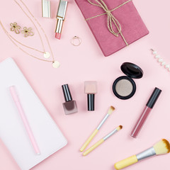 Naklejka premium Flat lay home office desk. Female workspace with note pad, fashion accessories and make up products on pink background. Fashion or beauty blogger concept.