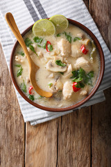 Thai chicken soup tom kha gai close-up in a bowl. Vertical top view from above