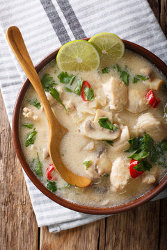 Thai soup tom kha gai from chicken with vegetables in coconut milk close-up in plate. Vertical top view from above