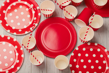 Disposable paper utensils of red and white color on a gray wooden background.