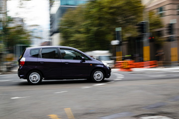 Fototapeta na wymiar Car in motion on the road, Sydney, Australia. Car moving on the road, blurred buildings in background.