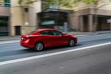 Foto op Canvas Red car in motion on the road, Sydney, Australia. Car moving on the road, blurred buildings in background. © AVPHOTOSALES