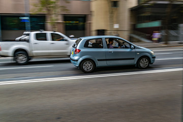 Fototapeta na wymiar Cars in motion on the road, Sydney, Australia. Cars moving on the road, blurred buildings in background.