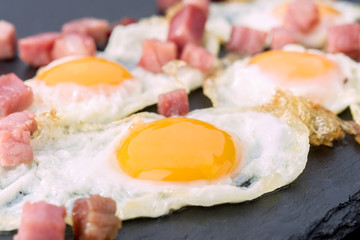fried quail egg with baked ham on black stone