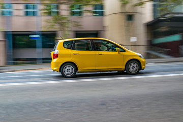 Yellow car in motion on the road, Sydney, Australia. Car moving on the road, blurred buildings in background. - obrazy, fototapety, plakaty